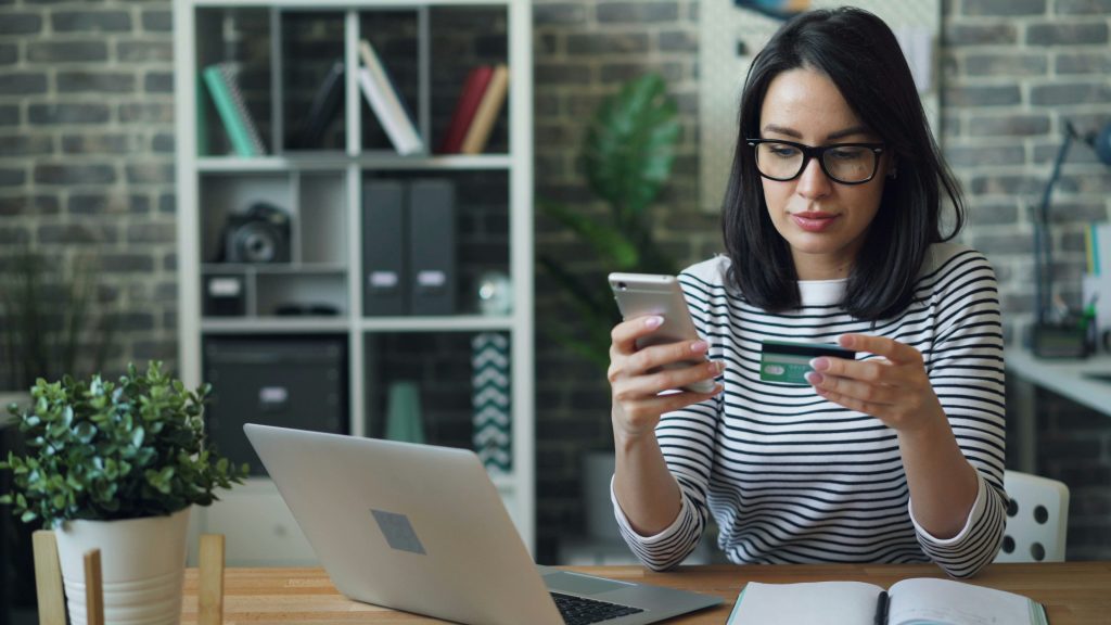 Woman entering credit card details on a laptop to make an online purchase
